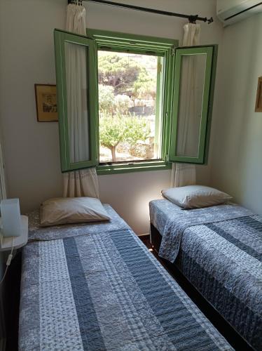 two beds in a room with a window at The house in the port in Korissia