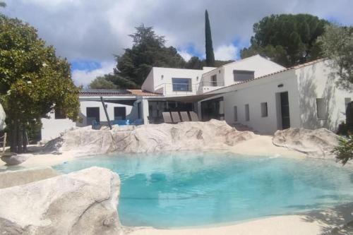 une piscine d'eau bleue devant une maison dans l'établissement Villa contemporaine avec lagon, à Sanary-sur-Mer