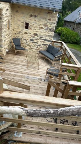 a wooden deck with two chairs and a table at Ty Oliv- entre terre et ocean in Plonéour-Lanvern