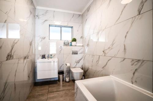 Un baño blanco con bañera y lavabo. en Tropical Beachfront Escape, en Ballito