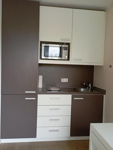eine Küche mit weißen Schränken und einer Mikrowelle in der Unterkunft Studio Suite near University in Bremen