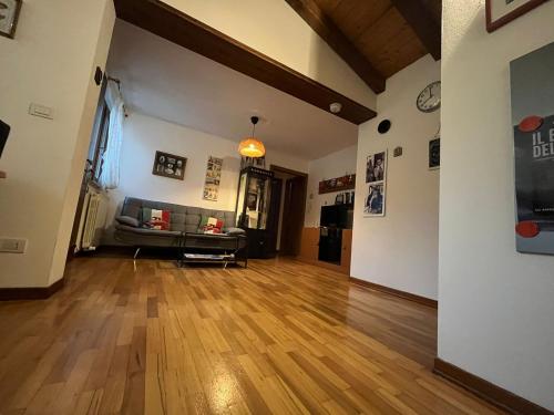 ein Wohnzimmer mit einem Sofa und Holzboden in der Unterkunft La Dolce Vita. Alloggio nel verde cuore del Friuli Venezia Giulia in Mariano del Friuli