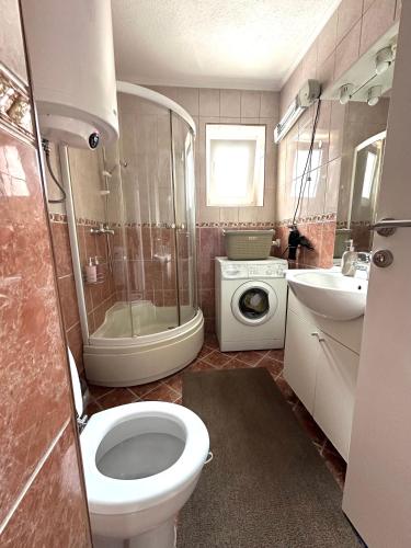 a bathroom with a toilet and a sink and a washing machine at Apartman Lara Laktasi in Laktaši