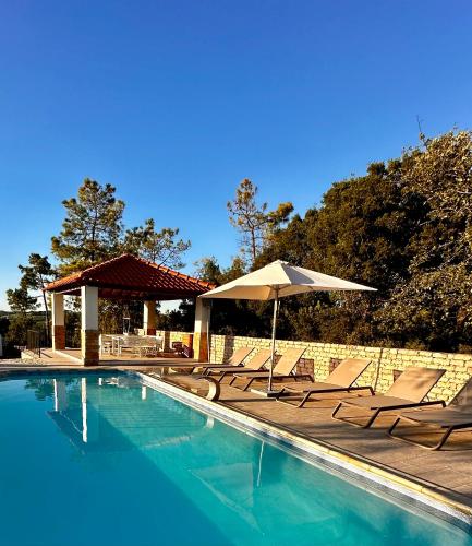 a swimming pool with chairs and an umbrella at Quinta Boa Vida in Alcobaça