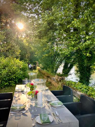 a table with plates and utensils with a view of a river at Château de La Tour en Brenne in Rivarennes
