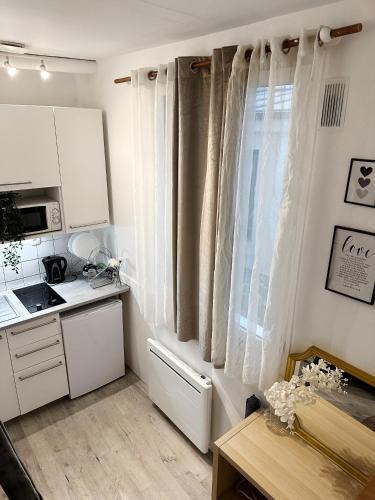 une cuisine avec des armoires blanches et une fenêtre dans l'établissement Studio Centre de Paris - Marais, à Paris