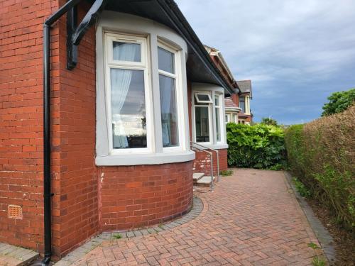 a brick house with a window and a brick sidewalk at Country Style Modern Self Catering 3 Bedroom Bungalow in Blackpool in Blackpool