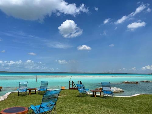 a group of chairs and tables on the beach at Blue Caribe Bacalar Front Lagoon in Bacalar