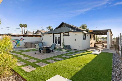 a backyard with a table and chairs on a lawn at Hummingbird Harmony House with BBQ and Hot Tub in Downtown Phoenix in Phoenix