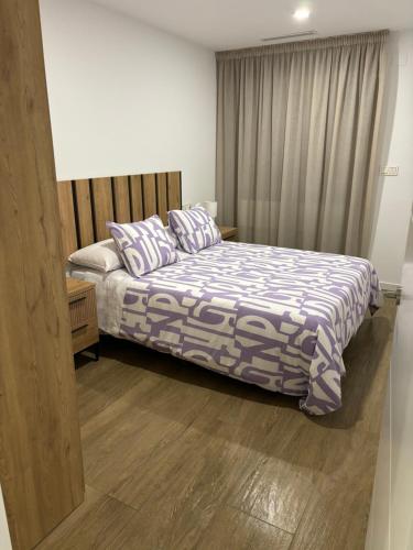 a bedroom with a bed with a blue and white comforter at Apartamento Isabel in Caravaca de la Cruz