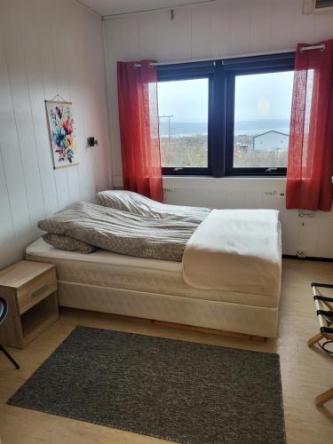 a bedroom with a bed and a window with red curtains at Odd inge Sør-Reime as in Nesseby
