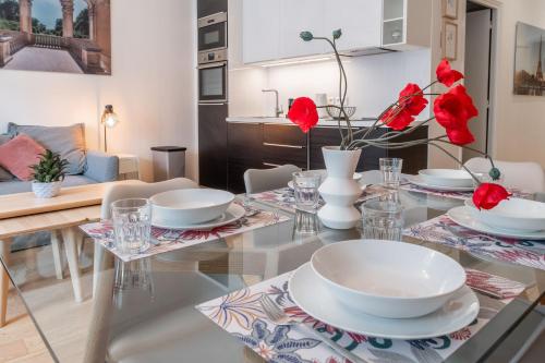 - une salle à manger avec une table en verre et des fleurs rouges dans l'établissement Appartement spacieux et rénové, à Paris