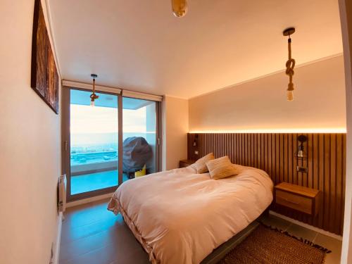 a bedroom with a bed and a large window at Departamento Concon con Terraza y vista al mar in Concón