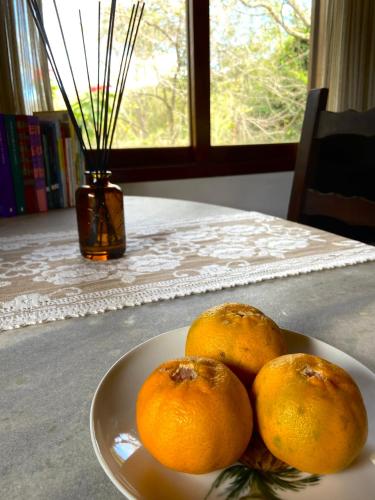 a plate of oranges on a table with a window at Chalé aconchegante em Mury in Nova Friburgo