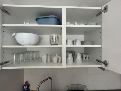a kitchen cabinet filled with white dishes and a sink at Ferienwohnung Ella in Marktoberdorf