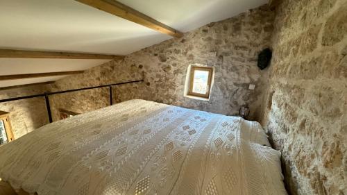 une chambre avec un lit dans un mur de pierre dans l'établissement Le logis, à Mons