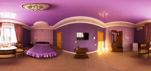 Habitación púrpura con cama, mesa y sillas en Alladin Hotel, en Oremburgo