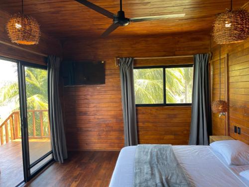 a bedroom with wooden walls and a bed and windows at Blue Caribe Bacalar Front Lagoon in Bacalar
