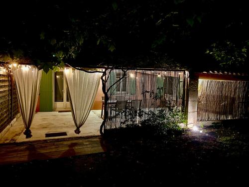 a gate with curtains and lights in a yard at night at Domaine Plan des Devens in Roussillon