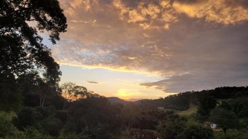a view of a sunset from a hill with trees at Chácara Alto do Vale in Bueno Brandão