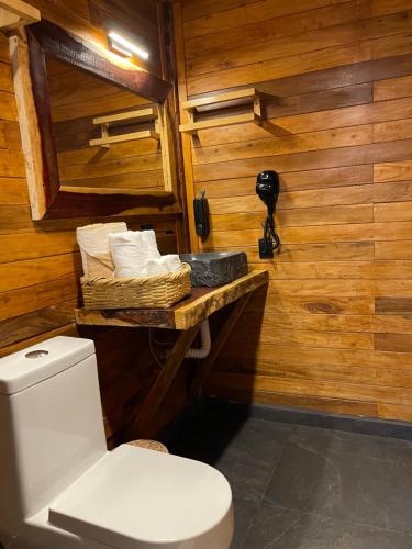 a bathroom with a toilet and a wooden wall at Blue Caribe Bacalar Front Lagoon in Bacalar