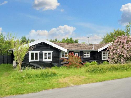 a black house with white windows and a tree at 6 person holiday home in Græsted-By Traum in Græsted