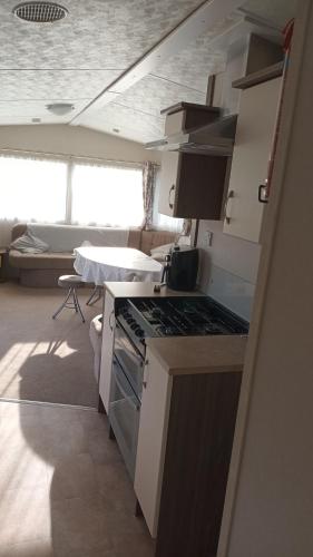 a kitchen with a stove and a living room at Butlins minehead caravan 120 River cove passes included in Minehead