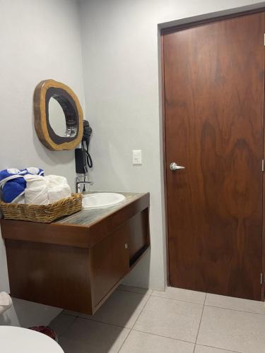 a bathroom with a sink and a wooden door at Blue Caribe Bacalar Front Lagoon in Bacalar
