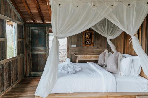 a bedroom with a white bed with a canopy at D'Ume Bendoel Homestay in Jatiluwih