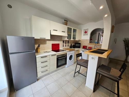 Il comprend une cuisine équipée d'un réfrigérateur, d'une table et de chaises. dans l'établissement MICHELE FAMILY - Centre ville - 2 Pièces tranquille - A 150 m de la mer, à Menton