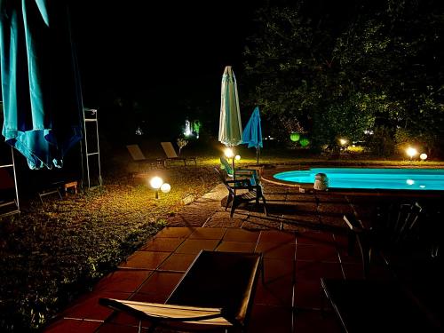 ein Pool mit Stühlen und Sonnenschirmen in der Nacht in der Unterkunft Domaine Plan des Devens in Roussillon
