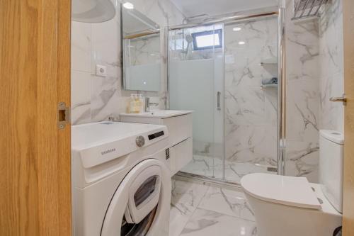 a white bathroom with a washing machine in it at Unique 1BD Ocean View AC Wi-Fi Beach 100m in Armação de Pêra