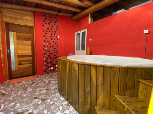 a bathroom with a tub in a red wall at Chalés Sitio Mangala in Itapeva