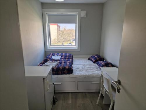 um pequeno quarto com uma cama e uma janela em Privat room in shared 3 rooms apartment Manglerud em Oslo