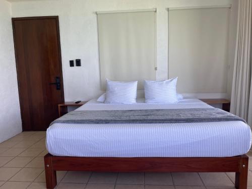 a bedroom with a large bed with white sheets and pillows at Blue Caribe Bacalar Front Lagoon in Bacalar