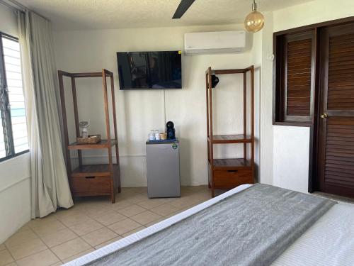 a bedroom with a bed and a refrigerator and a window at Blue Caribe Bacalar Front Lagoon in Bacalar
