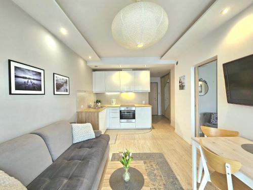 ein Wohnzimmer mit einem Sofa und einem Tisch in der Unterkunft Apartament Nice View -16piętro, parking podziemny, blisko morza in Danzig