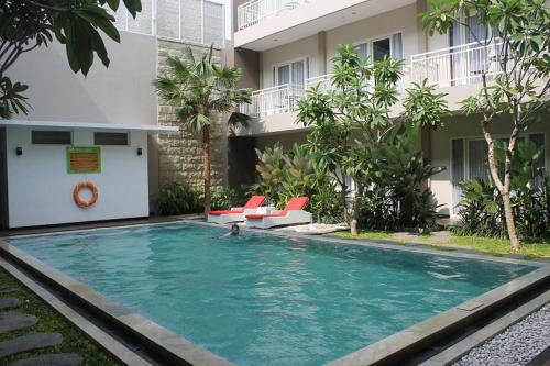 a person in a swimming pool next to a building at Choice Stay Hotel Denpasar in Denpasar