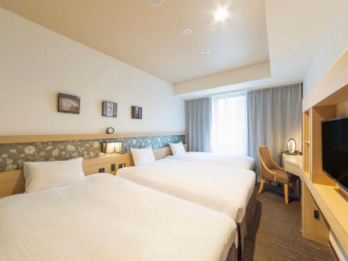 Habitación de hotel con 2 camas y TV de pantalla plana. en Hotel Keihan Yodoyabashi, en Osaka