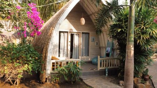 龍目島的住宿－吉利瑪蒂基酒店，一个带长凳和植物的门廊的房子