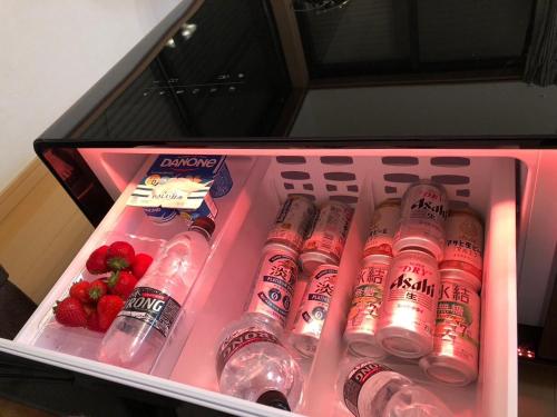 Un recipiente rosa lleno de botellas de agua y fresas. en ととのいのいえ千葉富津, en Minato