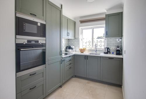 a kitchen with gray cabinets and a sink and a window at Renovated 2BD AC Wi-Fi Pool Beach 350m in Porches
