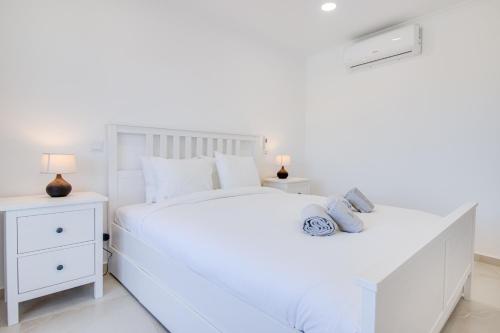 a white bedroom with a large white bed and two night stands at Renovated 2BD AC Wi-Fi Pool Beach 350m in Porches