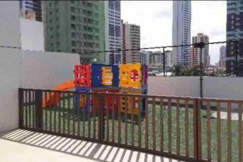 a fence with colorful play equipment in a city at Apartamento Dimensional Home Service - Manaíra in João Pessoa