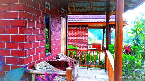 a red brick building with a bench on a porch at Ariel Bungalow Tetebatu in Tetebatu