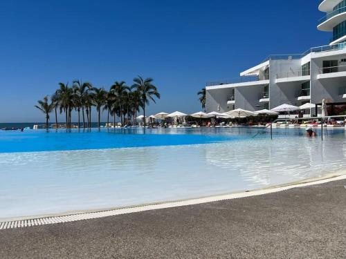 une grande piscine avec palmiers et parasols dans l'établissement Aria Ocean Playa Nuevo Vallarta, à Nuevo Vallarta