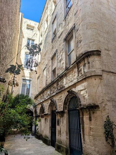 un ancien bâtiment en pierre avec une porte dans une rue dans l'établissement L'escale secrète - Emplacement central premium, à Nîmes