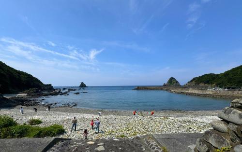 un groupe de personnes sur une plage près de l'eau dans l'établissement 魚の宿【海と西】, 