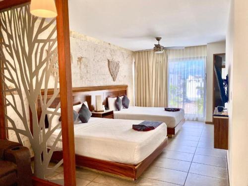 a hotel room with two beds and a tree mural at Grand Fifty Suites in Playa del Carmen
