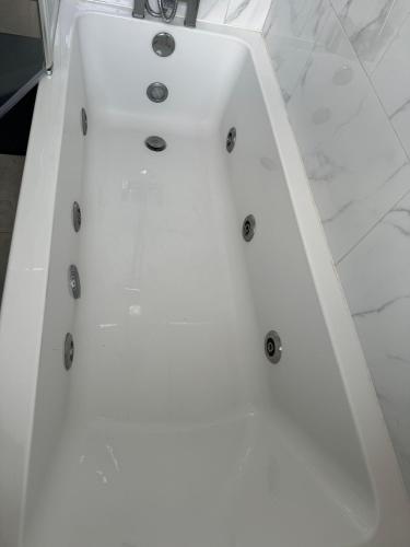 a white bath tub sitting in a bathroom at Instant Home in Luton